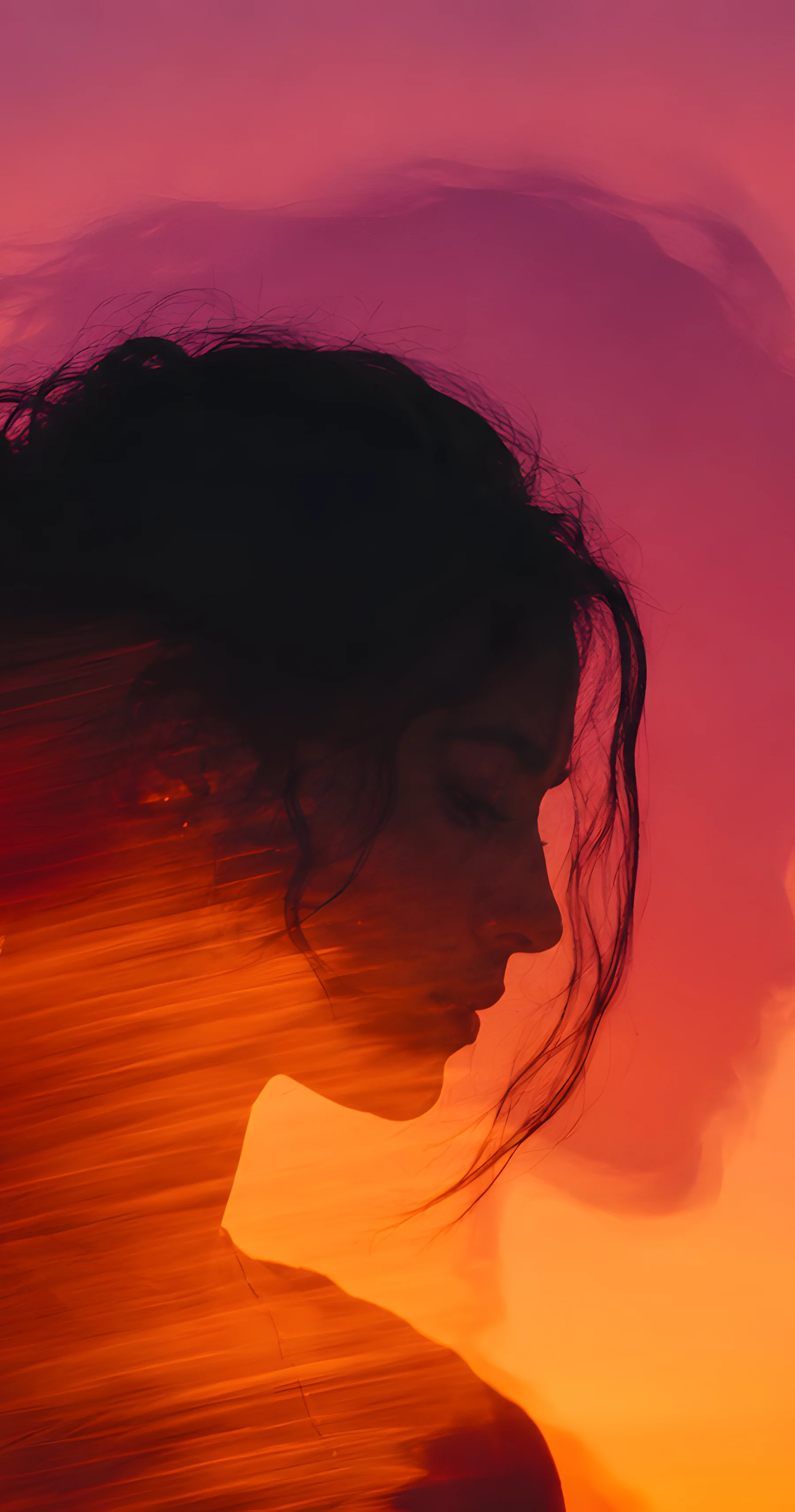 Profil d'une femme pensive, tête baissée, sur un ciel de coucher de soleil.